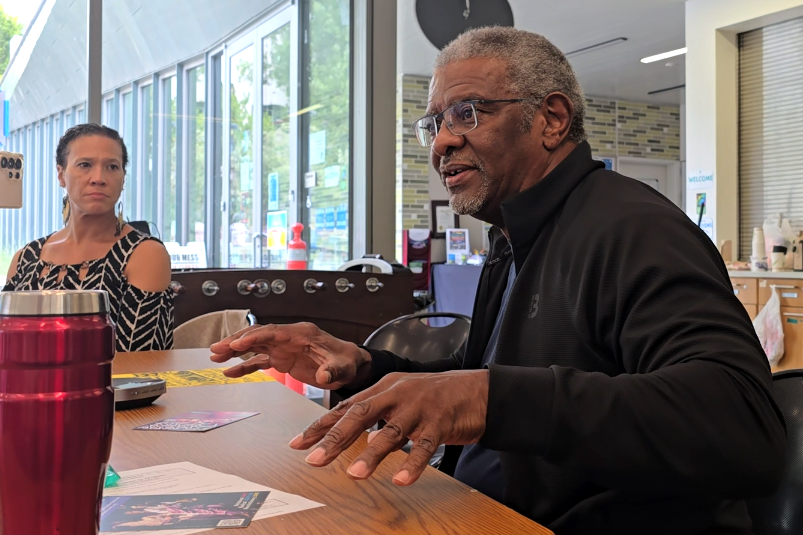 Joe Wilson gesticulates as he addresses attendees at a recent community meeting. One attendee, Rebecca Jackson of organization Community Forward, looks on.